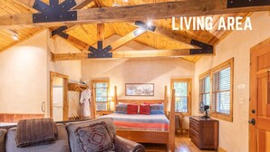 A cozy living area with a sofa, a bed, and a wooden ceiling. - Homey Cabin with Jacuzzi Near Ski Apache (Ruidoso)