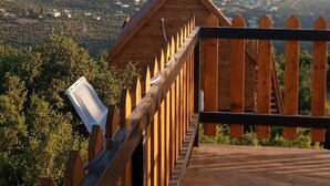 A wooden observation deck with a clear view of a town and hills in the distance. - orchid huts (Ajloun)