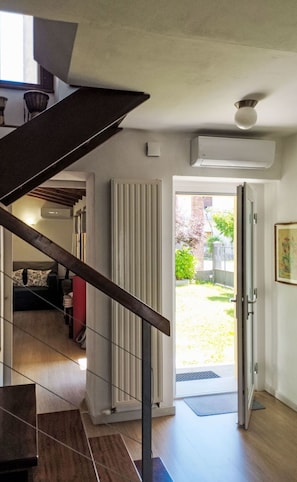 Un intérieur moderne avec un escalier menant à un espace de vie, un radiateur et une porte donnant sur un espace extérieur.