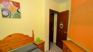 Ein Schlafzimmer mit einem hölzernen Bett, einem Schminktisch, einem Nachttisch und einer Tür mit einer verzierten Griff.