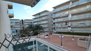Un edificio residencial de varios pisos con balcones, mobiliario exterior y un patio empedrado.