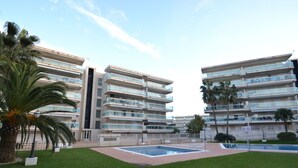 Un moderno edificio de apartamentos con varios balcones, piscina y césped bien cuidado.