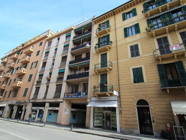 Un edificio a più piani con balconi, vetrine e cielo sereno.