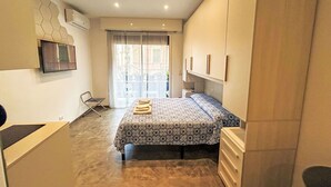 A compact hotel room with a bed, a TV mounted on the wall, and a small desk area. - Cosy apartment for 2 guests with A/C, WIFI, TV and balcony (Rapallo)