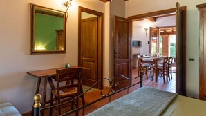 A room with a wooden ceiling, a bed, a desk with a chair, a table with chairs, and a mirror on the wall. - Cosy apartment in villa for 2 guests with WIFI, A/C, TV, terrace and pets allowed (Massa Marittima)