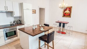 A modern kitchen with white cabinets, a wooden island, and a dining area with a red table and clear stools. - Nice apartment for 4 people with WIFI, TV and balcony (Vienna)