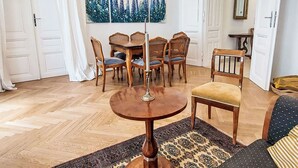 A dining area with a round table and six chairs, a painting above the table, and a patterned rug on the floor. - Nice apartment for 4 people with WIFI, TV and balcony (Vienna)