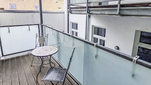 A balcony with a glass railing, a small round table, and a metal chair. - Nice apartment for 4 people with WIFI, TV and balcony (Vienna)