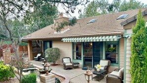A house with a patio, outdoor furniture, and a small garden.