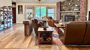 A spacious living room with a fireplace, leather furniture, and a bookshelf.
