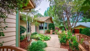 A residential property with a covered porch, a well-maintained garden, and a pathway leading to the house.