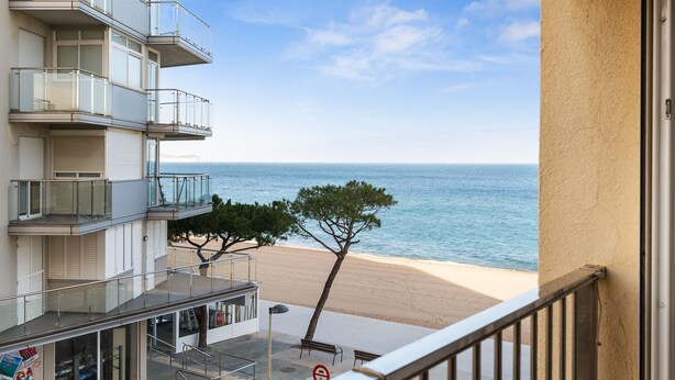 Un edificio de varios pisos con balcones que dan a una playa.