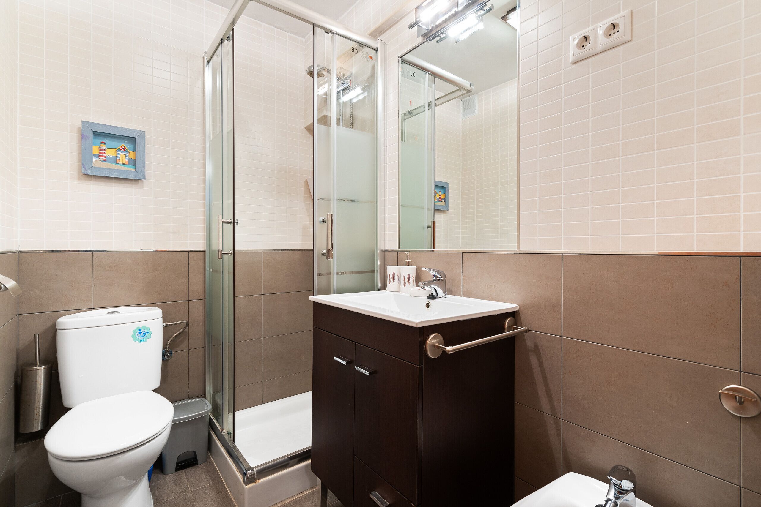 Une salle de bain équipée de toilettes, d’une douche, d’un lavabo et d’un miroir.