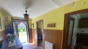 Um corredor com porta de madeira, um radiador e uma pequena mesa com um vaso de flores.