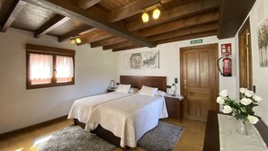 A bedroom with a double bed, wooden ceiling beams, a nightstand, a bedside table, a wall-mounted fire extinguisher, and a door labeled "SALIDA". - Casa El Molín 3 Soto de Dueñas (Soto)