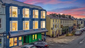 A row of buildings with shops and a green storefront. - Apartment 295 - Clifden - sleeps 5 guests  in 2 bedrooms (Clifden)