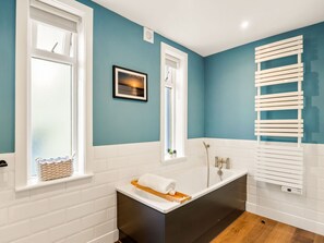 A modern bathroom with a bathtub, a window with a towel rack, and a picture on the wall. - Apartment 295 - Clifden - sleeps 5 guests  in 2 bedrooms (Clifden)