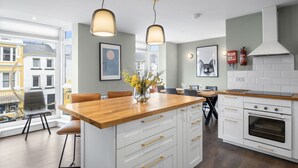 A modern kitchen with white cabinetry, a wooden countertop, pendant lights, and a view of the city. - Apartment 295 - Clifden - sleeps 5 guests  in 2 bedrooms (Clifden)
