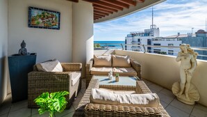 A balcony with wicker furniture, a statue, and a painting. - Le Sunset/Cap Sud by Interhome (Cap d'Agde)