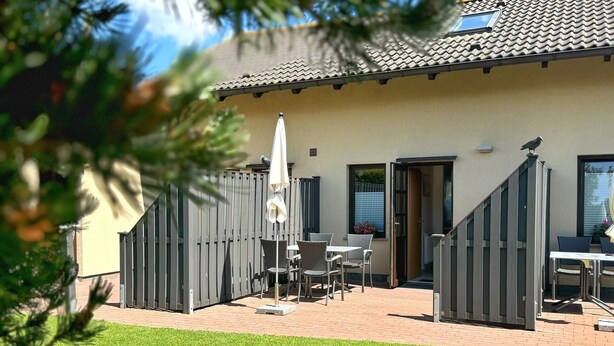 Ein Patio mit Tisch, Stühlen, Sonnenschirm und Holzlattenzaun.