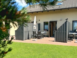 Un espace patio aménagé avec une table et des chaises, un parasol et une clôture en bois.