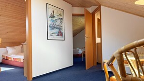 Ein gemütliches Zimmer mit einem Bett, einem Sessel und einem gerahmten Bild an der Wand.
