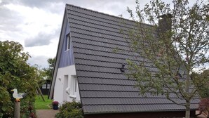 Il s’agit d’un bâtiment traditionnel, doté d’un toit en pente, d’une façade blanche et d’une enseigne bleue indiquant qu’il s’agit d’une maison familiale.