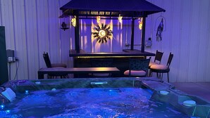 A hot tub with blue lighting, a wooden table, and chairs in a covered outdoor area. - A retreat near Elephant Butte Lake with awesome views. Don’t miss out. Enjoy! (Elephant Butte)