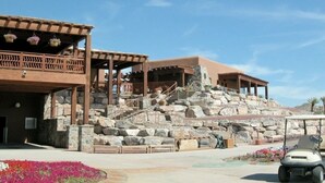 A building with a stone staircase leading to a terrace, a covered area with wooden railings, and a golf cart in the foreground. - A retreat near Elephant Butte Lake with awesome views. Don’t miss out. Enjoy! (Elephant Butte)