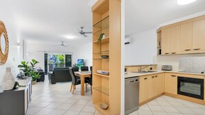 Eine moderne Küche mit Holzausstattung, einem Einbauofen und einem Essbereich mit Tisch und Stühlen.