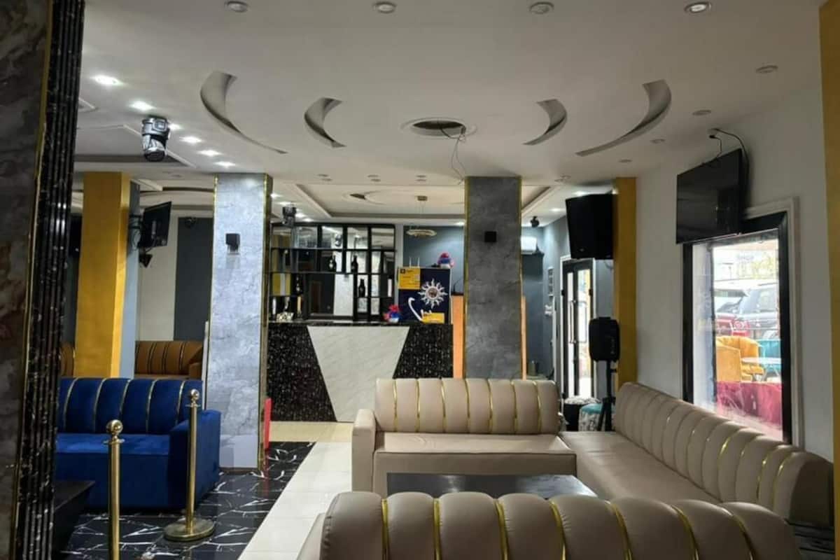 Un hall con un sofá, un sillón azul y una recepción.