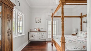 Een slaapkamer met een hemelbed, een dressoir en een spiegel.