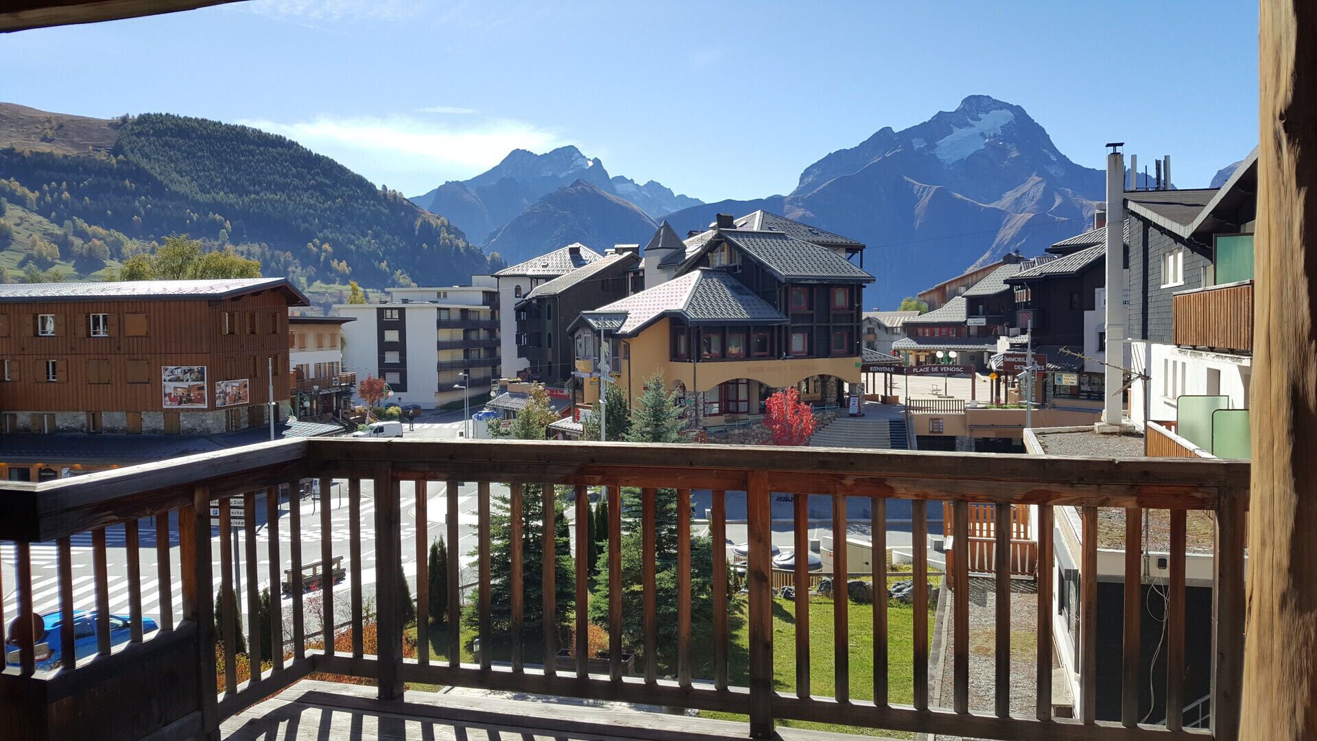 En balkon med udsigt over en by, med bygninger og bjerge i baggrunden.