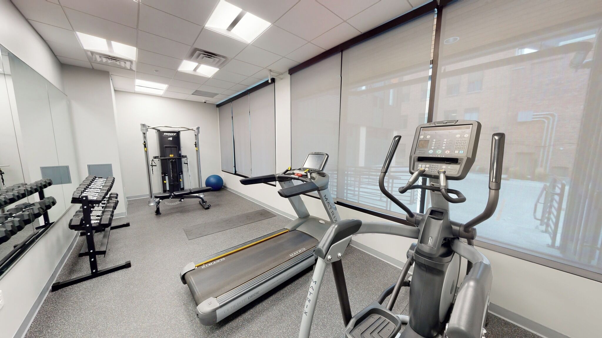 A gym with cardio equipment, weight machines, and a mirrored wall.
