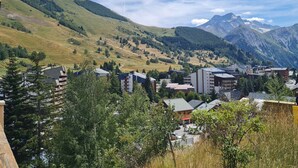 A mountainous town with buildings, including a hotel with multiple floors and a flat roof. - Wonderful apt 4/6 ppl, mountain view (Les Deux Alpes)