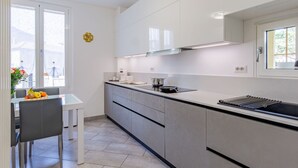 A modern kitchen with white cabinets, a black countertop, and a window with curtains.