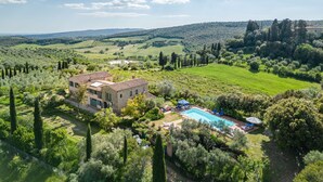 Eine Villa mit Swimmingpool, umgeben von üppiger Vegetation und Weinbergen.