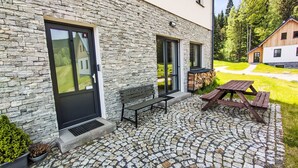 A stone building with a black door, a bench, and a picnic table on a cobblestone patio. - 13ka Ground Oasis with Terrace by Interhome (Smržovka)