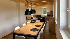 Un comedor moderno con una mesa de madera, sillas blancas y lámparas colgantes negras.
