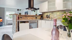 Una cocina moderna con armarios blancos, salpicadero de piedra y una isla central.