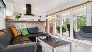Un salón moderno con un sofá de cuero negro, un sillón gris y una mesa de centro de madera.