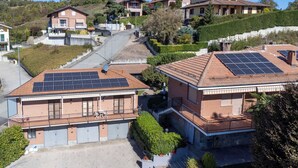 Ein Wohngebiet mit Häusern, die mit Solaranlagen, einem gepflasterten Einfahrtsweg und einer hügeligen Landschaft versehen sind.