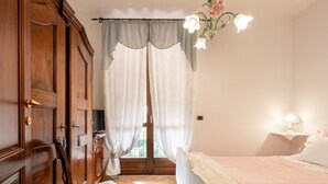 Ein Schlafzimmer mit Bett, Stuhl, Kleiderschrank und einem Fenster mit Vorhängen.