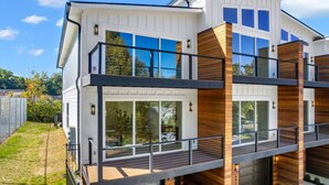 Et moderne hus med to etager, store vinduer, en balkon og en garage.