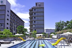Zona de piscina de hotel con un tobogán amarillo, sillas de descanso y sombrillas.
