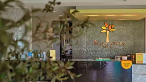 A reception desk with a logo for 'Live Tree Hotel' and a sign indicating 'Car Parking'. - Olive Tree Hotel (Sattahip)