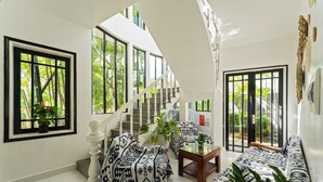 A modern interior with a staircase, large windows, and patterned furniture. - Luna Verde Hotel Hoi An (Da Nang)