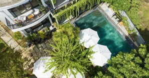 A modern building with a pool, outdoor seating, and lush greenery. - Luna Verde Hotel Hoi An (Da Nang)