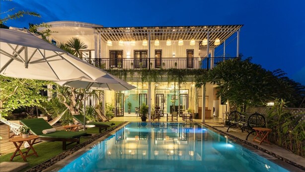 A two-story building with a pool, outdoor seating, and a covered patio area. - Luna Verde Hotel Hoi An (Da Nang)