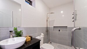A modern bathroom with a large white sink, a toilet, and a shower area. - Luna Verde Hotel Hoi An (Da Nang)